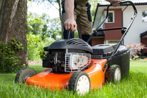 man starting lawnmower out in his yard